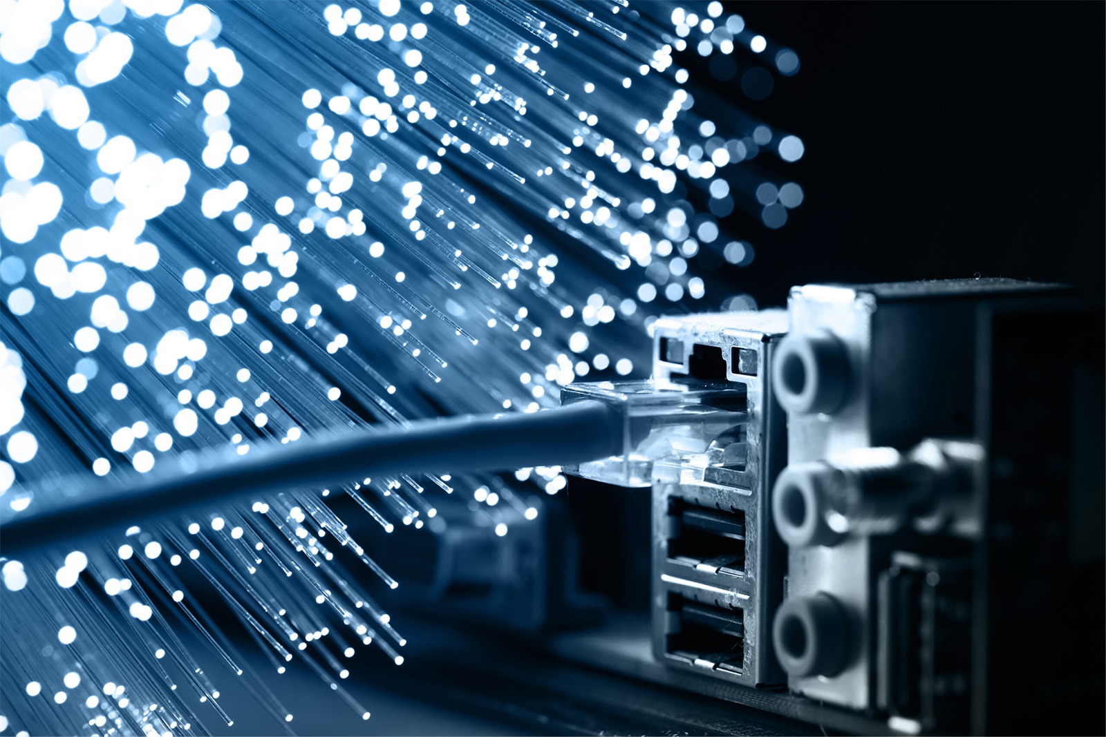 Close-up of a network connector plugged into a device, with blue light beams representing data transmission through fiber optics.